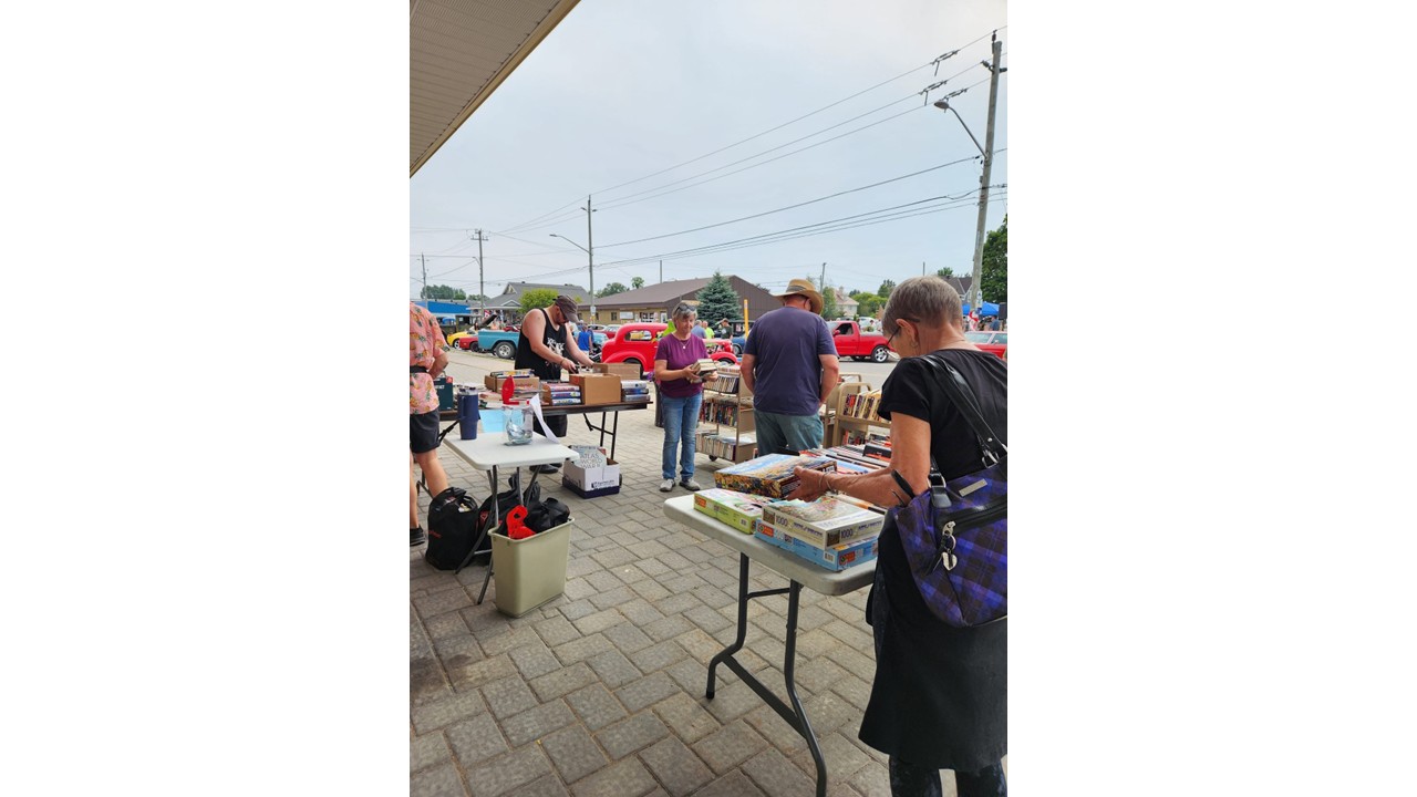 Neighbours browsing books and puzzles at an outdoor sale
